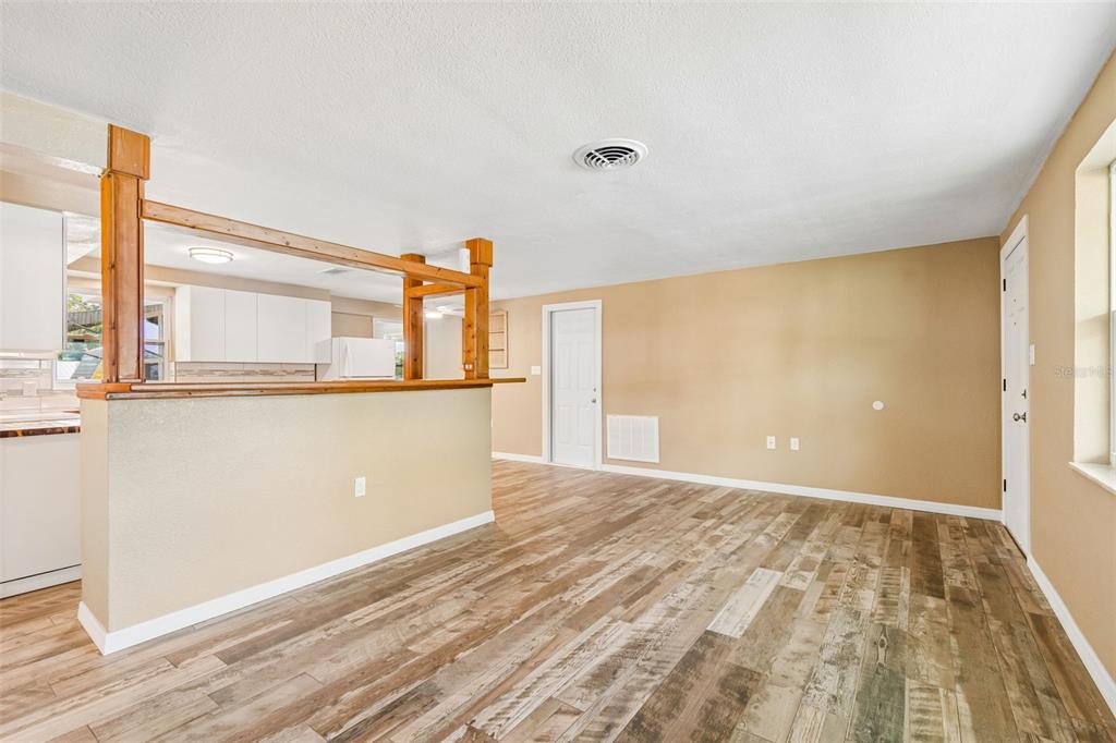 An interior view shows a red front door opening into a living area with wood-look flooring — 5046 FARLEY DRIVE, HOLIDAY, FL