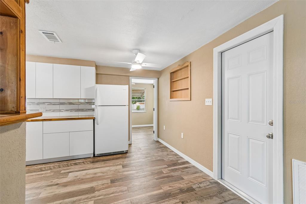 A living room with a white sofa and armchair faces a television and kitchen bar — 5046 FARLEY DRIVE, HOLIDAY, FL