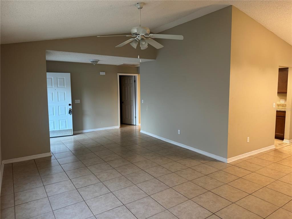 An open living area features tan tile flooring, a vaulted ceiling, and a ceiling fan — 2537 ARBORWOOD DRIVE, VALRICO, FL