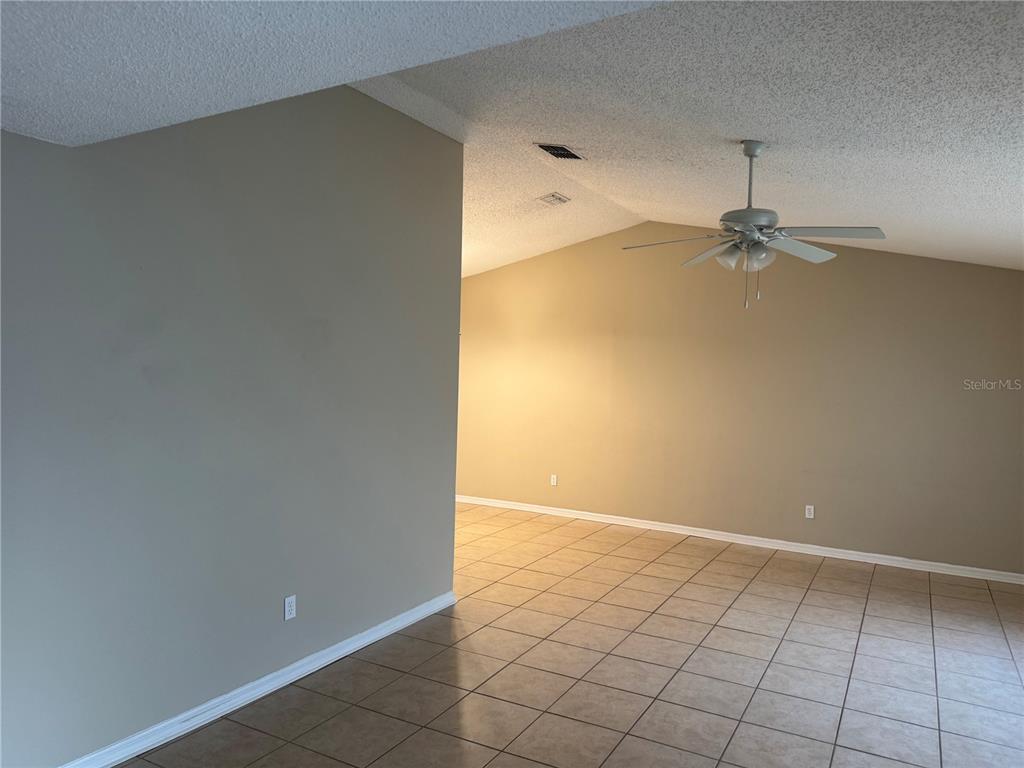 An interior view of a room with beige walls, tiled flooring, and a ceiling fan — 2537 ARBORWOOD DRIVE, VALRICO, FL