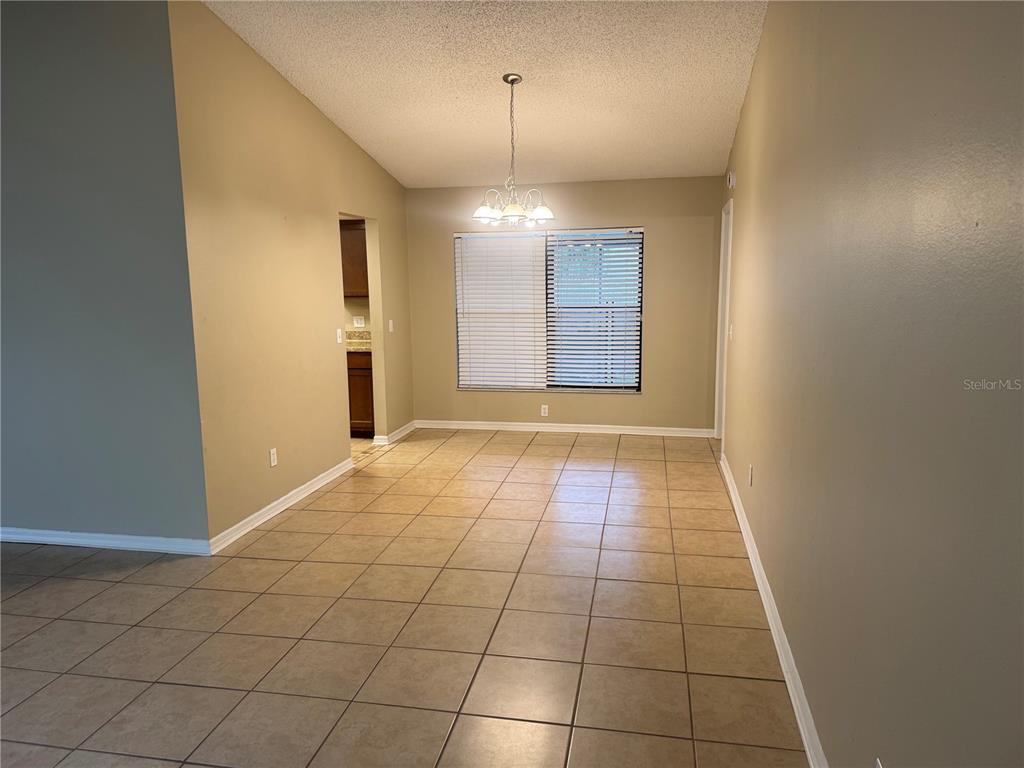 A dining room with beige walls, tile flooring, a chandelier, and a window with blinds — 2537 ARBORWOOD DRIVE, VALRICO, FL