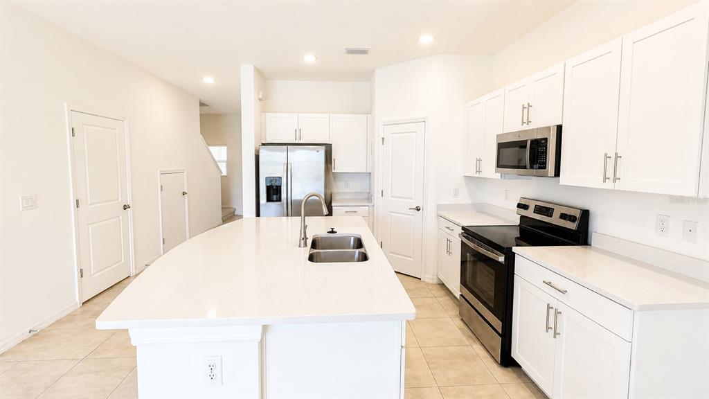 A bright kitchen features white cabinets, a central island with a sink, and stainless appliances — 5686 ARCHIPELAGO STREET, NOKOMIS, FL