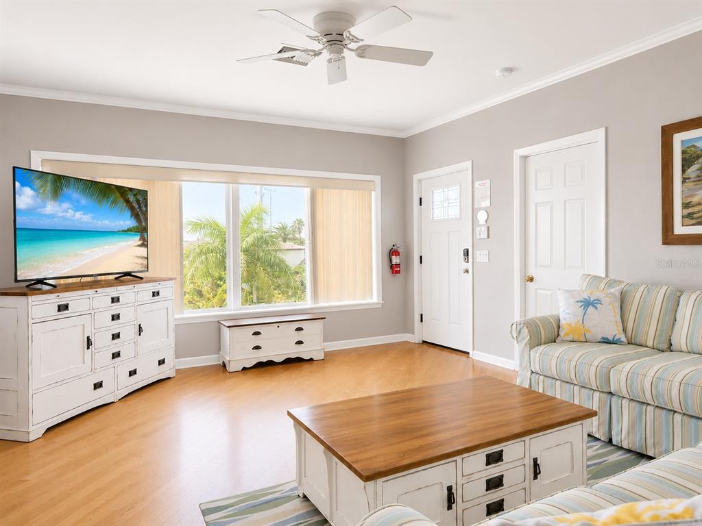 A living room features light wood floors, a white media console, and a striped sofa — 140 50TH STREET, HOLMES BEACH, FL