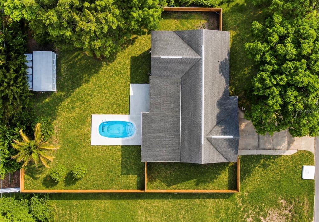 An aerial view shows a house with a gray roof, a pool, and a fenced yard — 3101 FLOWERTREE ROAD, BELLE ISLE, FL