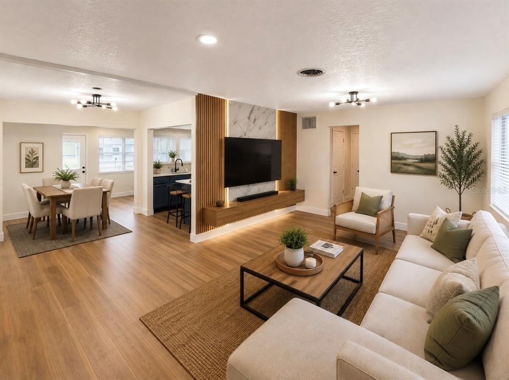 A living room with wood flooring, a marble-accented media wall, and an adjacent dining area — 3101 FLOWERTREE ROAD, BELLE ISLE, FL