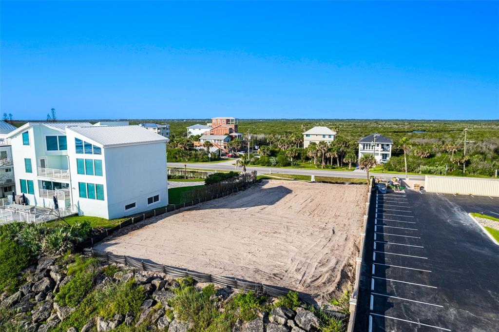 An aerial view shows a vacant, sandy lot situated between a white house and parking — 5575 S ATLANTIC AVENUE, NEW SMYRNA BEACH, FL