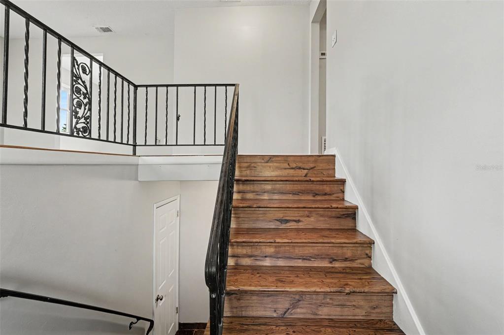 A wooden staircase with a black metal railing leads to an upper landing — 4406 URBAN COURT, ORLANDO, FL