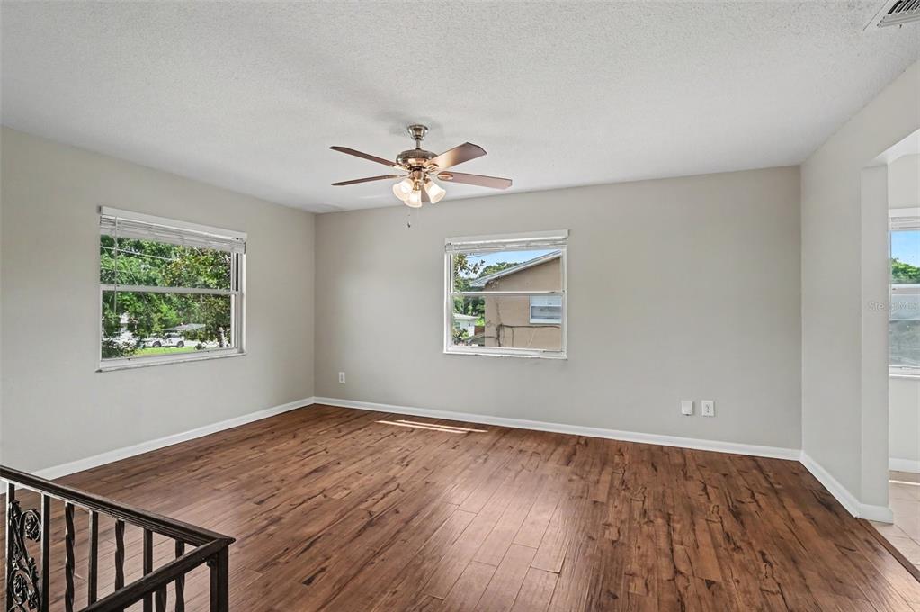 An empty room with wood-look flooring, a ceiling fan, and two windows on light-colored walls — 4406 URBAN COURT, ORLANDO, FL