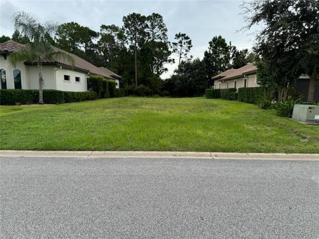 A vacant, grassy residential lot sits between two existing houses on a paved street — 327 HIBISCUS WAY, PALM COAST, FL