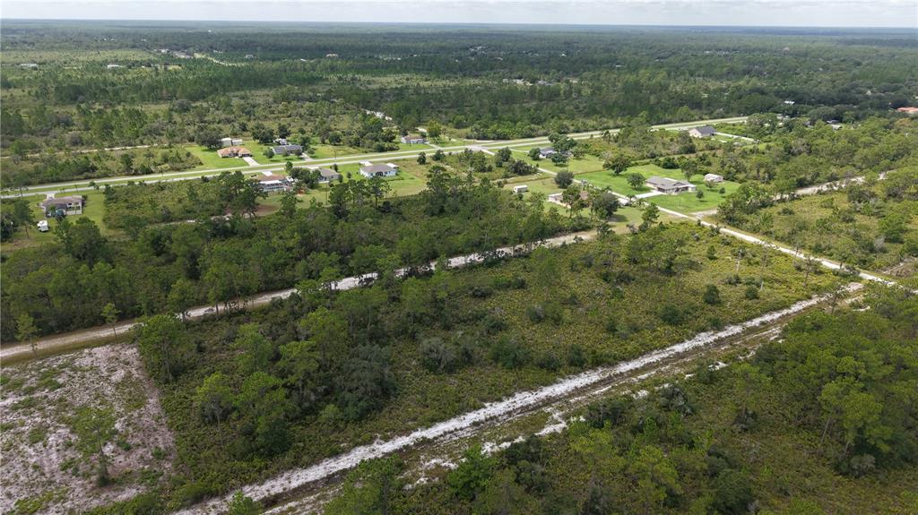 An aerial view shows a rural landscape with scattered houses, dirt roads, and wooded lots — EL DORADO, INDIAN LAKE ESTATES, FL