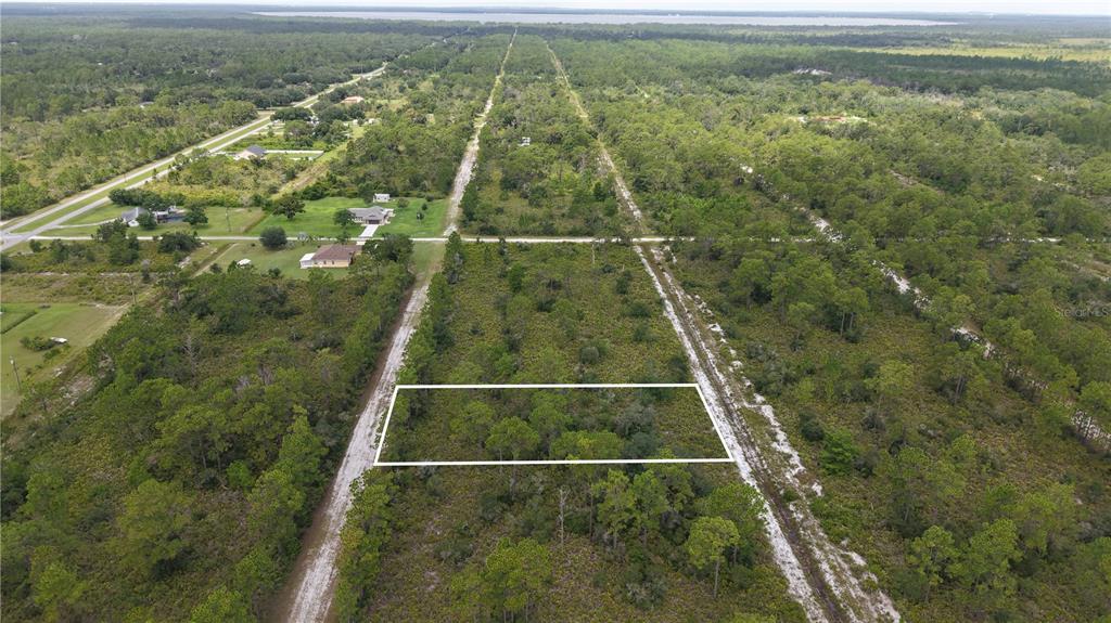 An aerial view shows a rectangular plot of land outlined in white amidst wooded terrain — EL DORADO, INDIAN LAKE ESTATES, FL