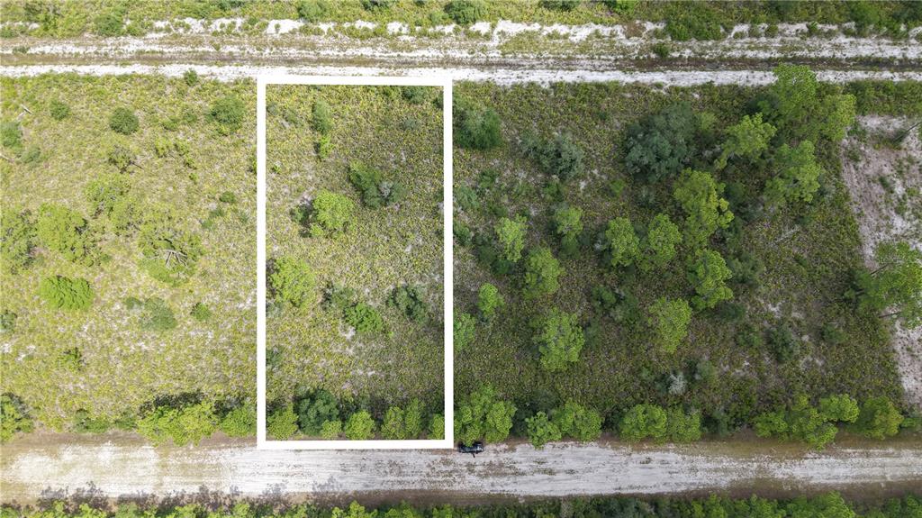 An aerial view shows a rectangular plot of land outlined in white between two dirt roads — EL DORADO, INDIAN LAKE ESTATES, FL