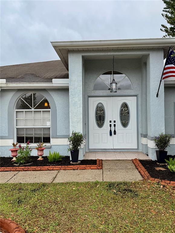 The exterior of a light blue house features a double front door and arched windows — 1813 DOCKSIDE DRIVE, VALRICO, FL