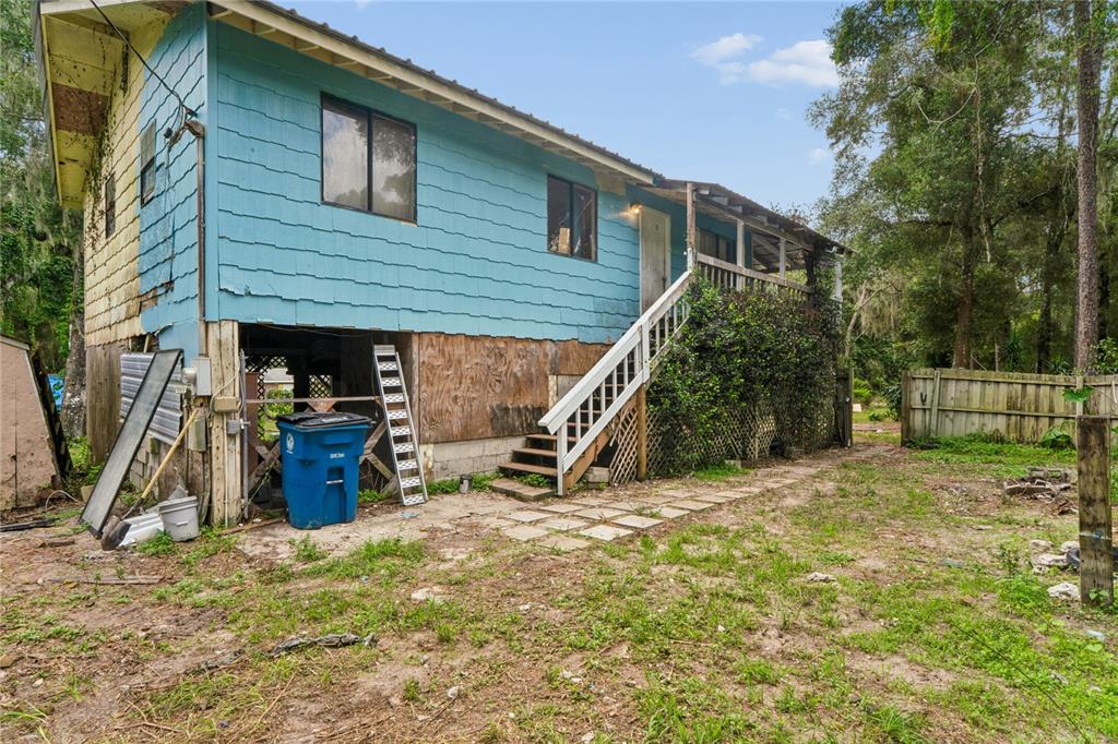 An elevated house with blue siding, a wooden staircase, and a partially enclosed lower level — 25141 KIBLER LANE, BROOKSVILLE, FL