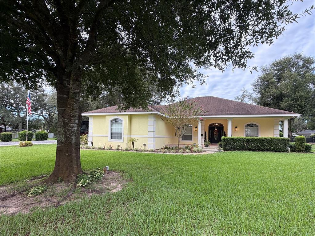 A yellow single-story house with a hip roof and a large front yard with trees — 52 PINE FOREST DRIVE, HAINES CITY, FL