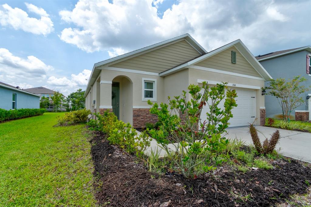 A single-story house with a beige exterior, stone accents, and a two-car garage — 1360 CORK DRIVE, ORMOND BEACH, FL