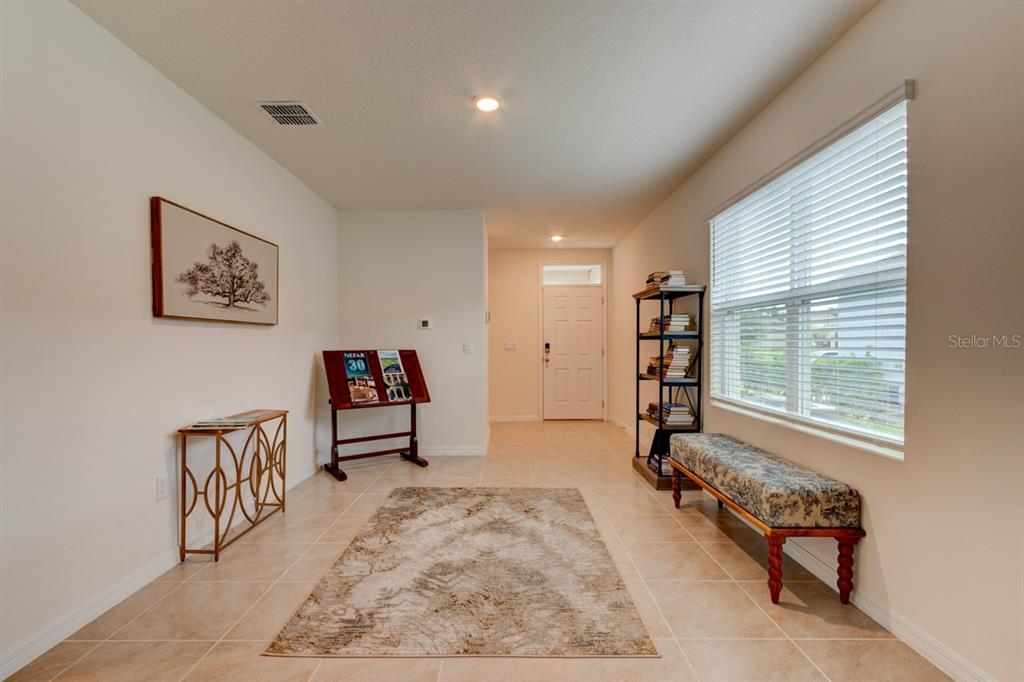 A tiled entryway features a patterned rug, a bench, a bookshelf, and a console table — 1360 CORK DRIVE, ORMOND BEACH, FL