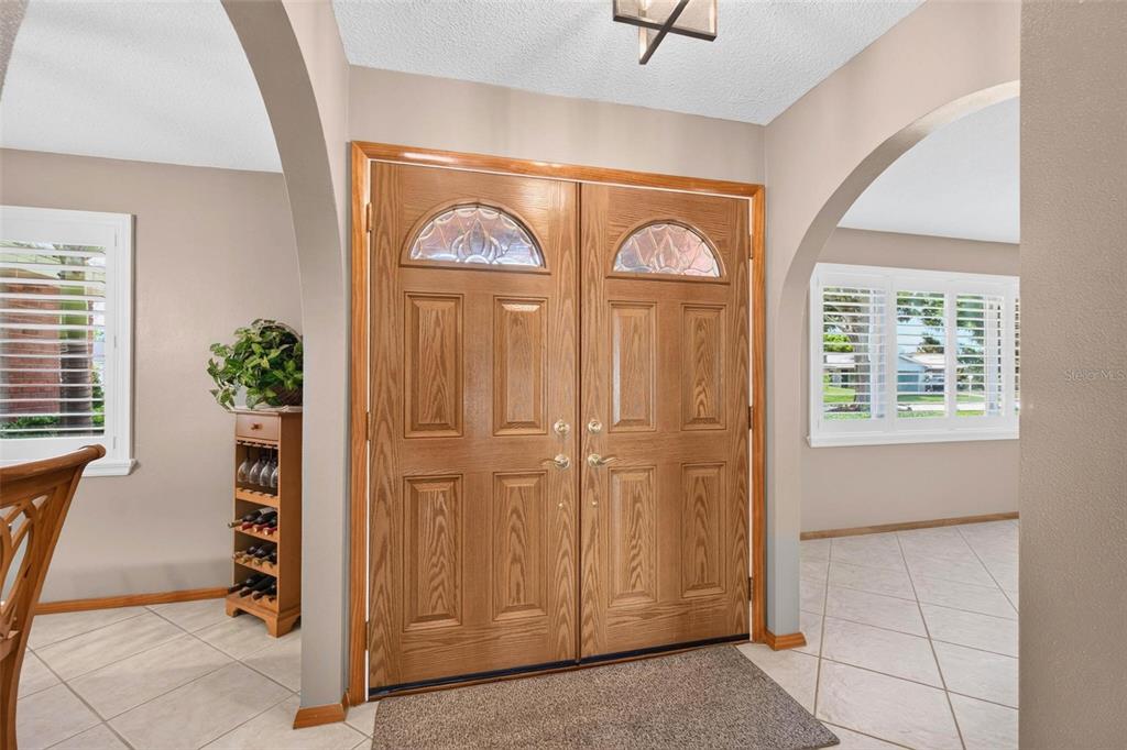 An entryway features double wooden doors with arched glass panels and light-colored tile flooring — 6225 43RD AVENUE N, KENNETH CITY, FL