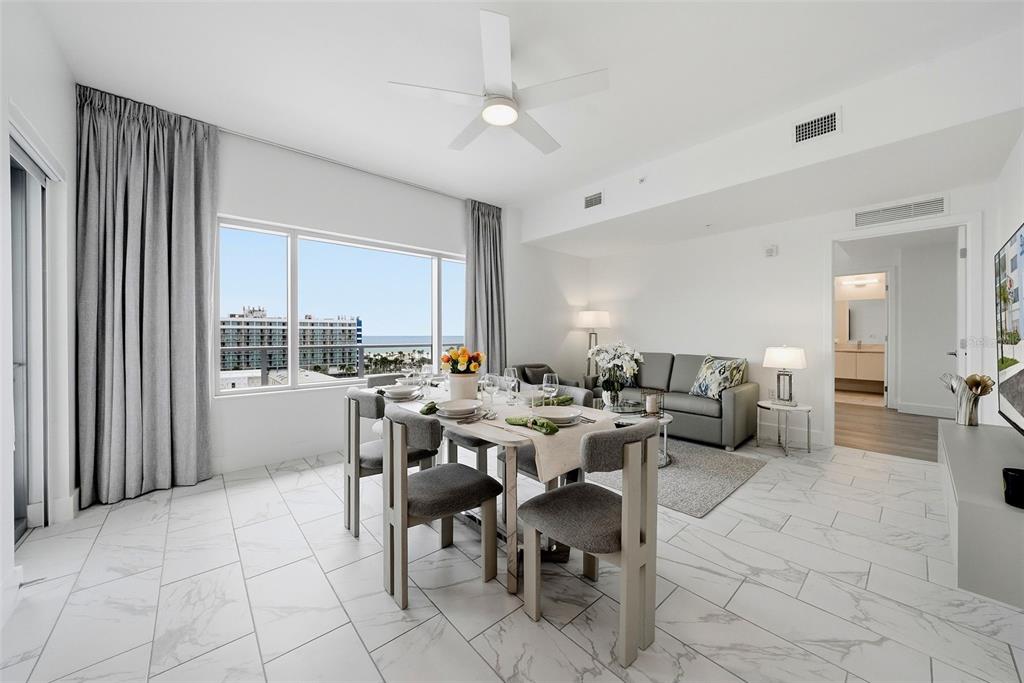 A dining area and living room with white tile floors, a ceiling fan, and ocean views — 411 E SHORE DRIVE UNIT 403, CLEARWATER BEACH, FL