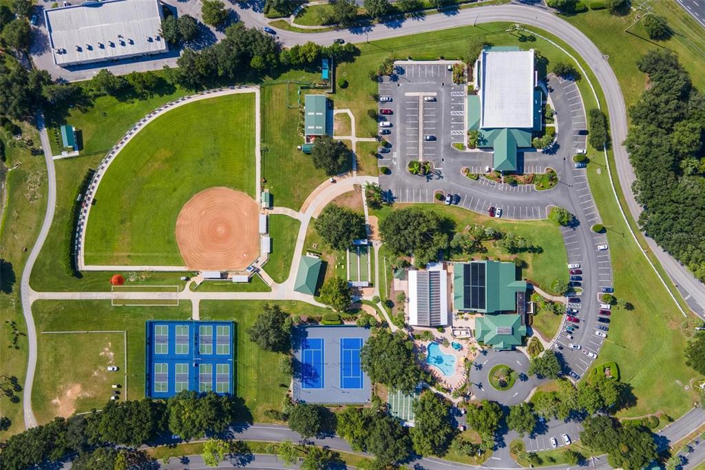 This aerial view shows a recreational facility with a baseball field, tennis courts, and buildings — 11614 SE 172ND LOOP, SUMMERFIELD, FL
