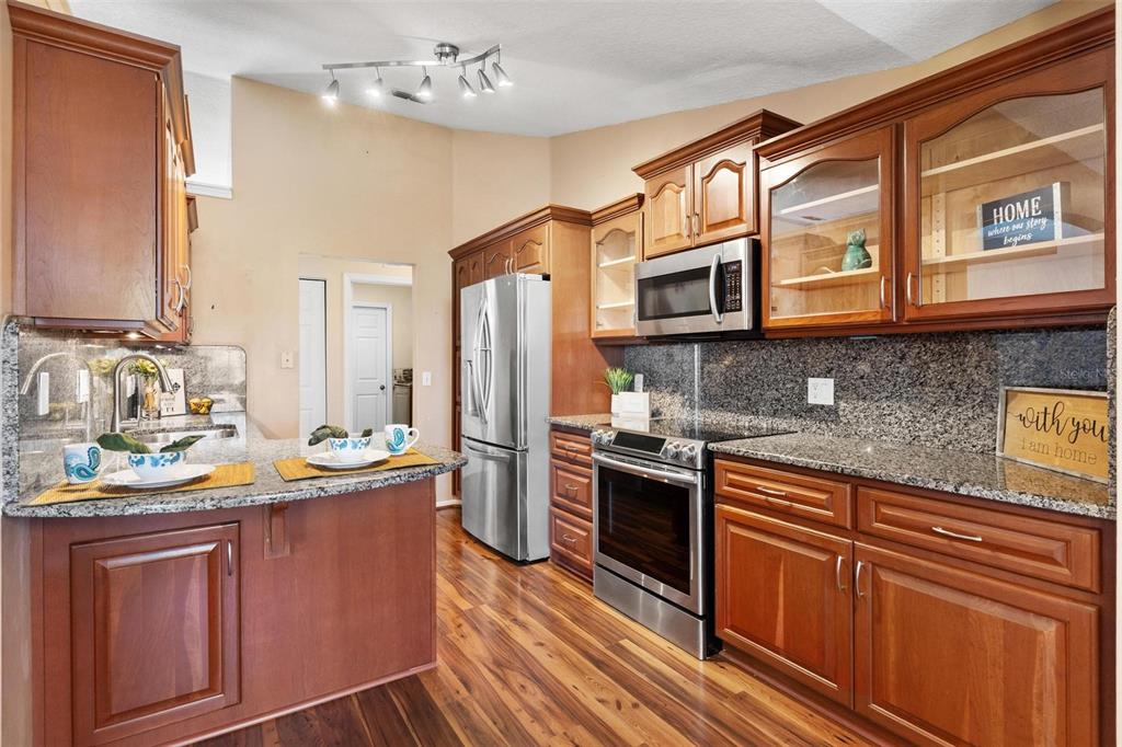 A kitchen with wood cabinets, granite countertops, stainless steel appliances, and hardwood flooring — 11614 SE 172ND LOOP, SUMMERFIELD, FL