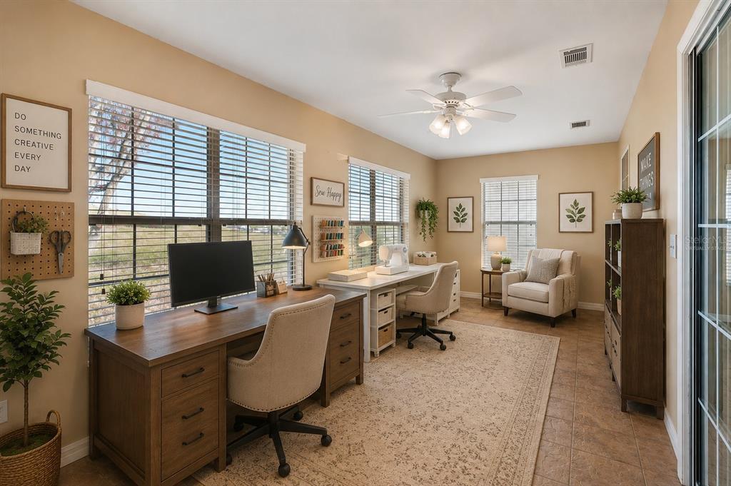 A home office features two desks, beige walls, tile flooring, and a ceiling fan — 11614 SE 172ND LOOP, SUMMERFIELD, FL