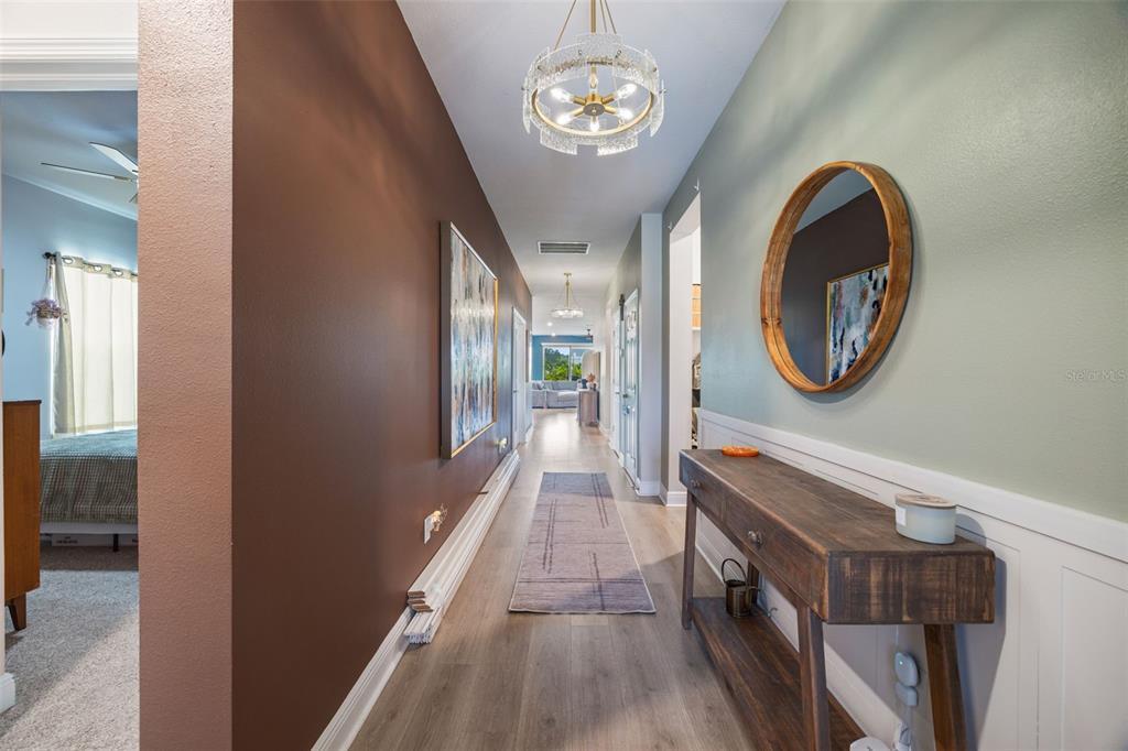 A hallway features a brown wall, a light green wall with wainscoting, and a wooden console — 11822 CHEVELON LANE, PARRISH, FL