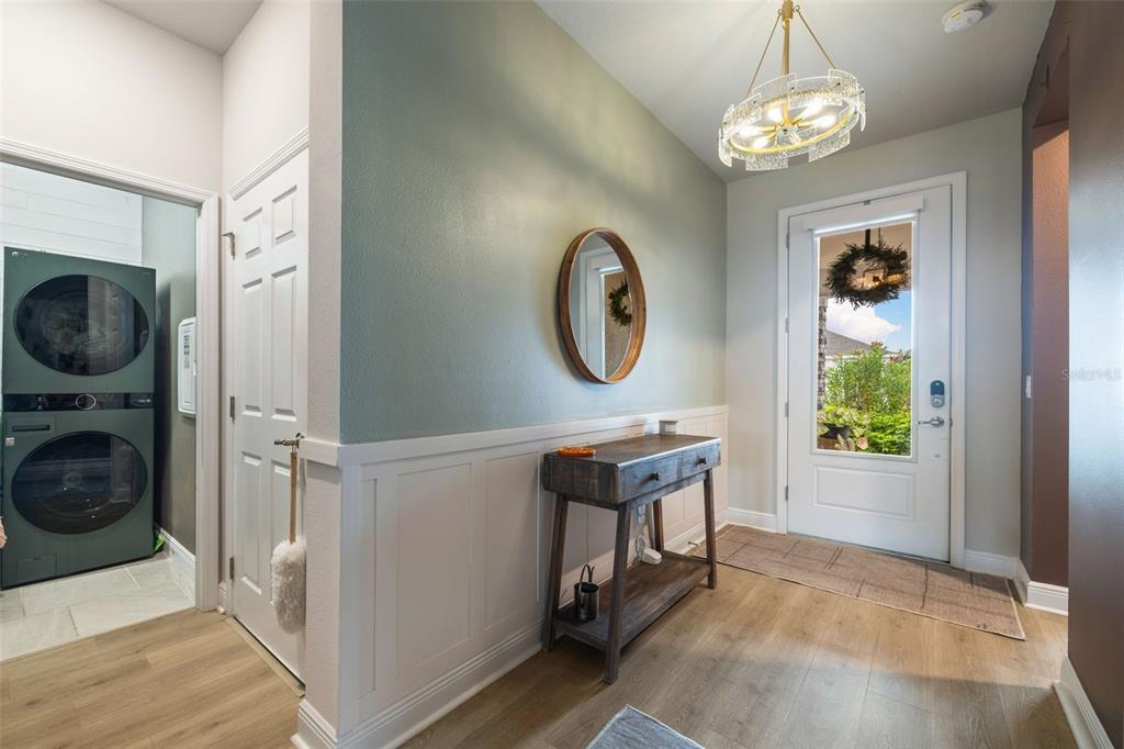 An entryway features a wood console table, a round mirror, wainscoting, and a glass-paneled door — 11822 CHEVELON LANE, PARRISH, FL