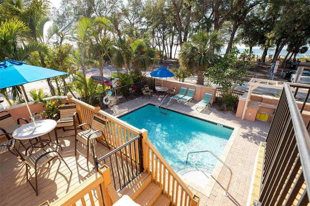 An elevated view of a swimming pool with lounge chairs and a wooden deck area — 102 39TH STREET UNIT 2, HOLMES BEACH, FL
