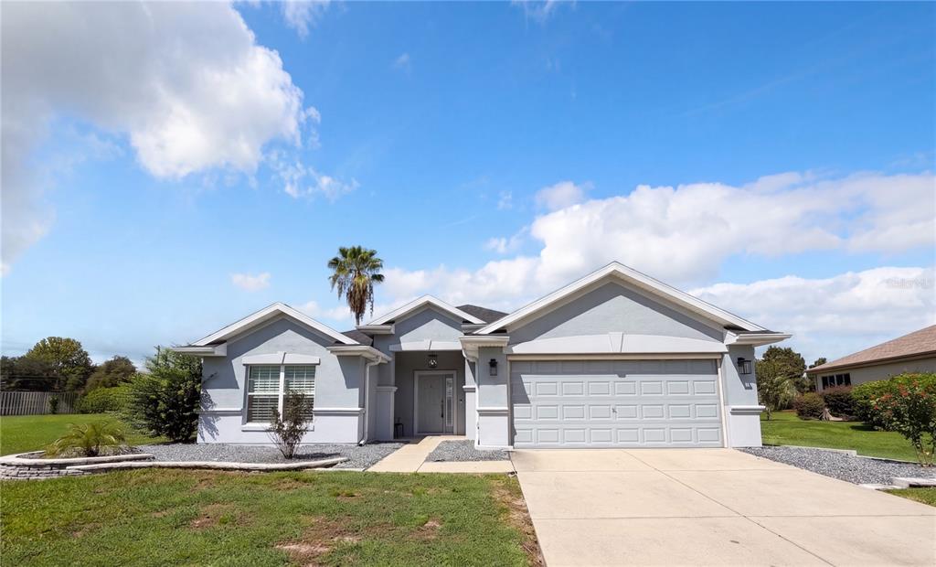 A single-story house with a gray stucco exterior, a two-car garage, and a concrete driveway — 13940 SE 95TH COURT, SUMMERFIELD, FL