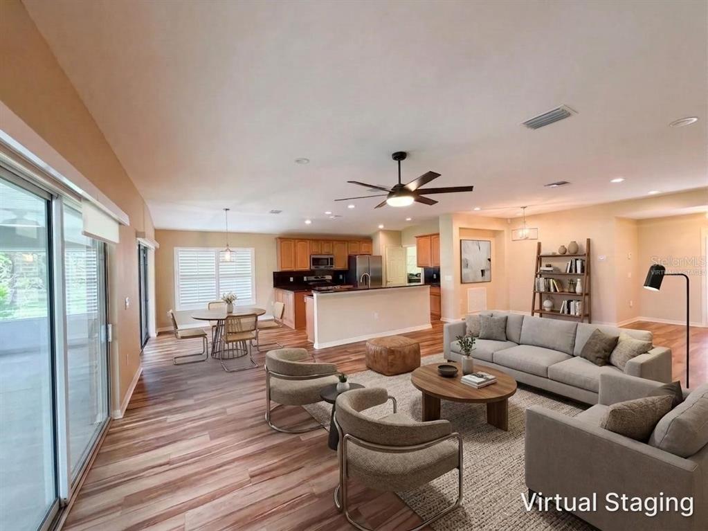 A living room and kitchen with wood-look flooring, a ceiling fan, and virtual staging furniture — 13940 SE 95TH COURT, SUMMERFIELD, FL