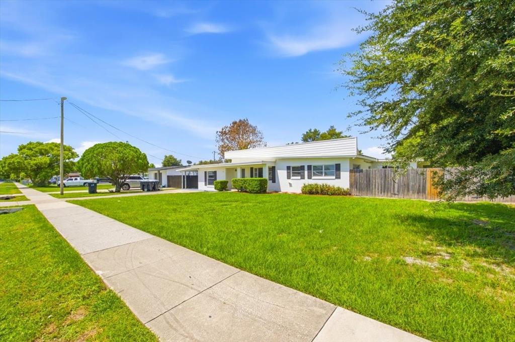 A white, single-story house with a flat roof, black shutters, and a wooden privacy fence — 6416 SHERYL ANN DRIVE, ORLANDO, FL
