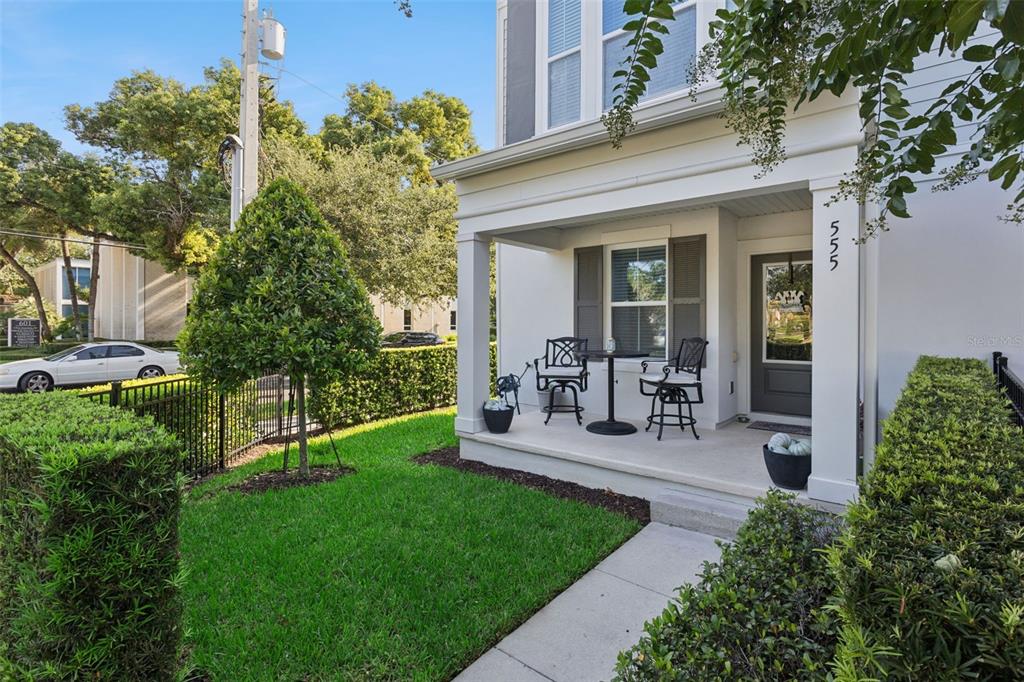 A front porch with a small table and two chairs sits beside a manicured lawn — 555 N FERN CREEK AVENUE UNIT 1, ORLANDO, FL