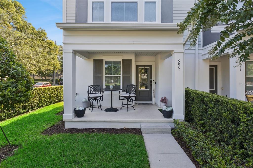 A front porch with two chairs and a small table sits before a gray door — 555 N FERN CREEK AVENUE UNIT 1, ORLANDO, FL