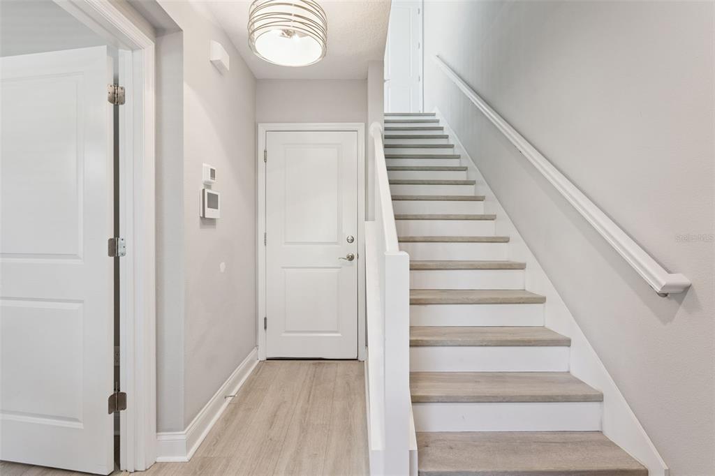 An entryway features light wood flooring, a white staircase, and a white front door — 555 N FERN CREEK AVENUE UNIT 1, ORLANDO, FL