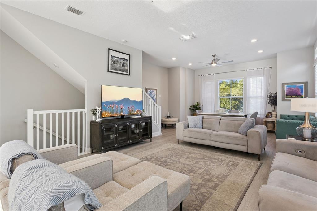 A living room features light wood flooring, a gray sectional sofa, and a television console — 555 N FERN CREEK AVENUE UNIT 1, ORLANDO, FL