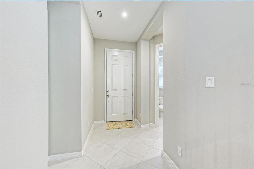 A tiled entryway features a white front door and a doorway leading to a bathroom — 5564 SUMMIT GLEN, BRADENTON, FL