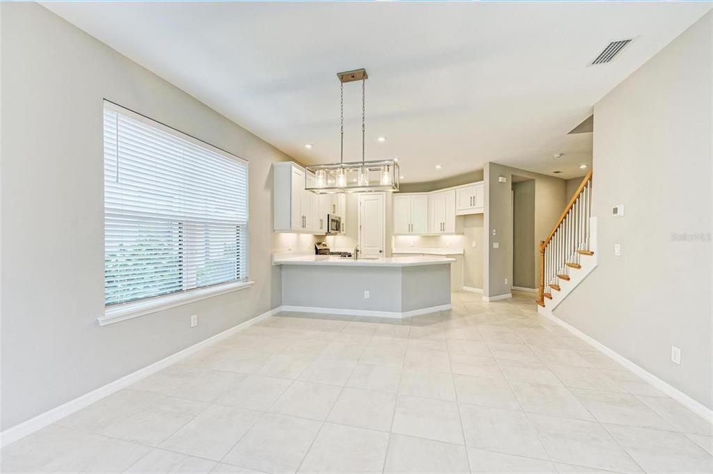 A bright kitchen with white cabinets and a breakfast bar opens into a dining area — 5564 SUMMIT GLEN, BRADENTON, FL