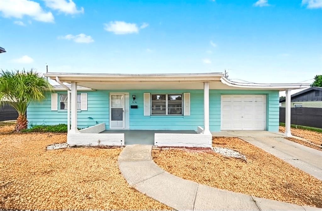 A light green, single-story house features a covered front porch, a garage, and gravel landscaping — 3630 WINDER DR, HOLIDAY, FL