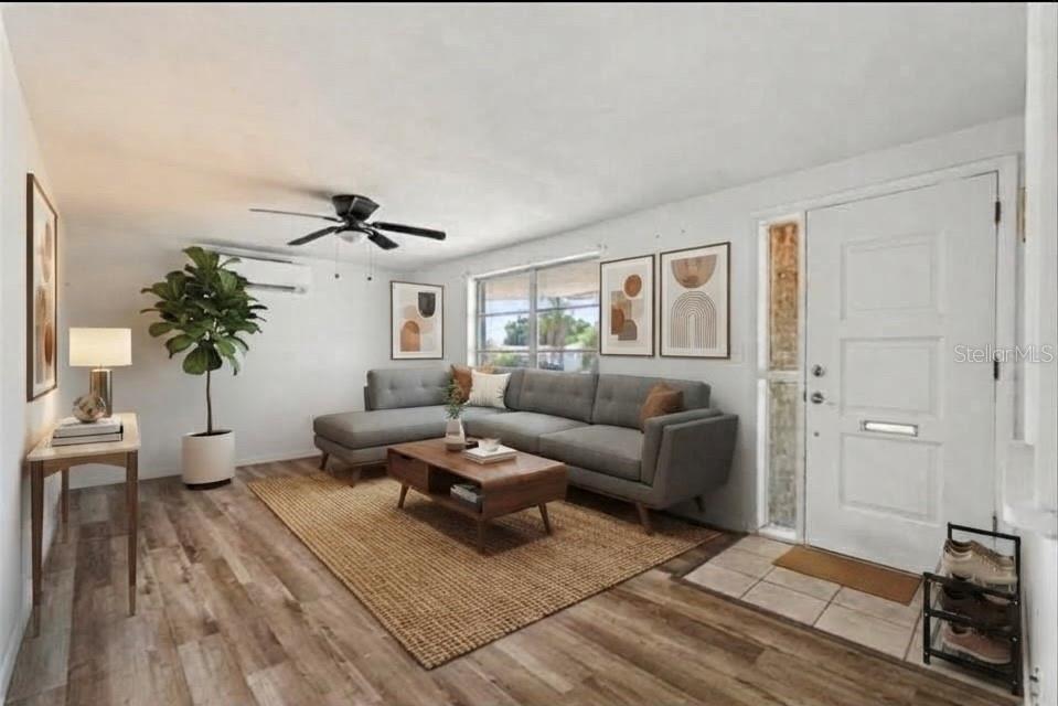 A living room with white walls, wood-look flooring, a ceiling fan, and a front door — 3630 WINDER DR, HOLIDAY, FL