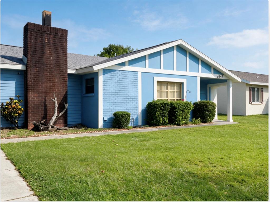 A blue house with a brick chimney and a white-trimmed gable roof sits on grass — 2846 LANCASTER ROAD, MELBOURNE, FL