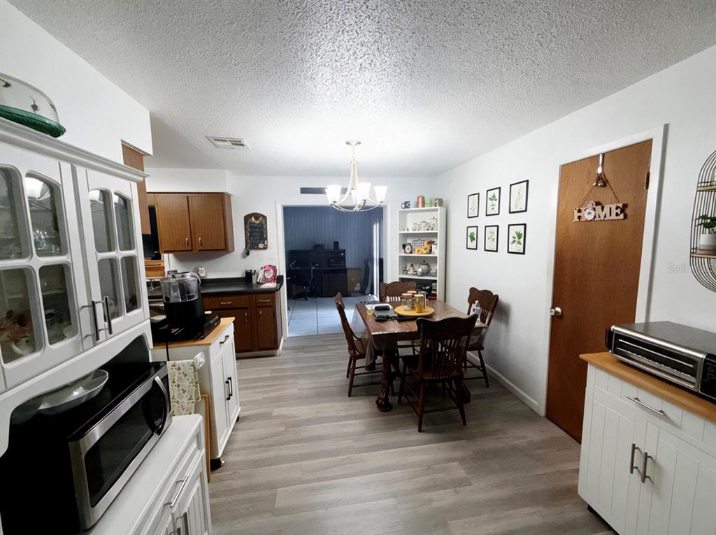 A dining area with a wooden table and chairs sits adjacent to a kitchen — 2846 LANCASTER ROAD, MELBOURNE, FL