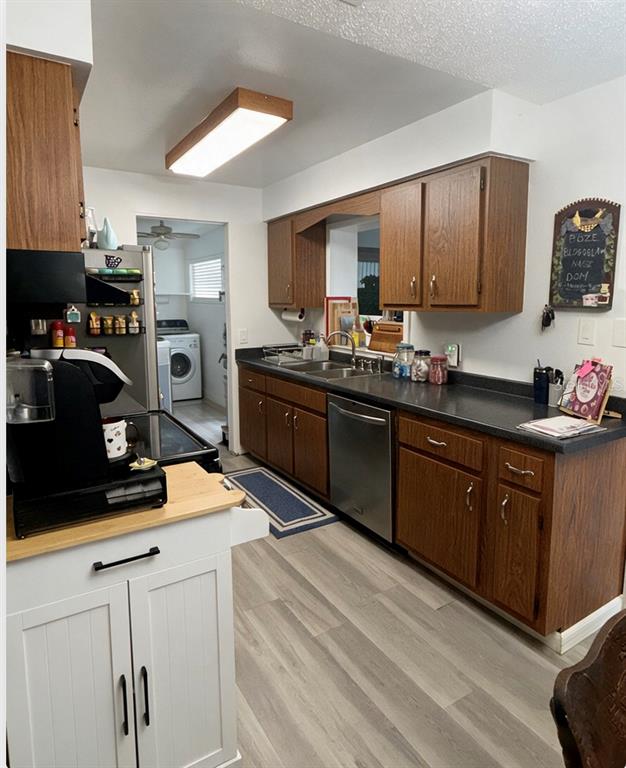 A kitchen features wood cabinets, dark countertops, stainless steel appliances, and light wood-look flooring — 2846 LANCASTER ROAD, MELBOURNE, FL