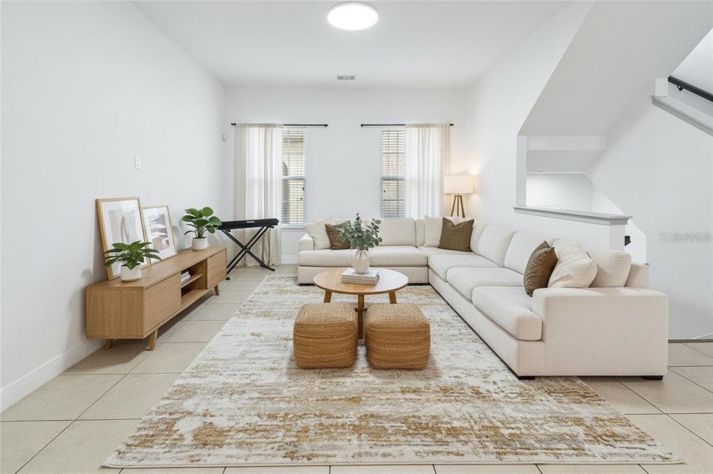 A bright living room features a large sectional sofa, a wooden media console, and tile flooring — 940 LOBELIA DRIVE, LAKE MARY, FL
