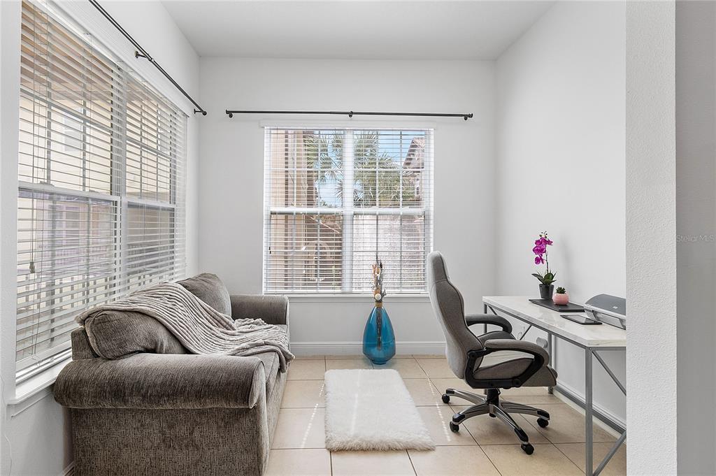 A home office features a gray sofa, a desk with a chair, and tile flooring — 940 LOBELIA DRIVE, LAKE MARY, FL