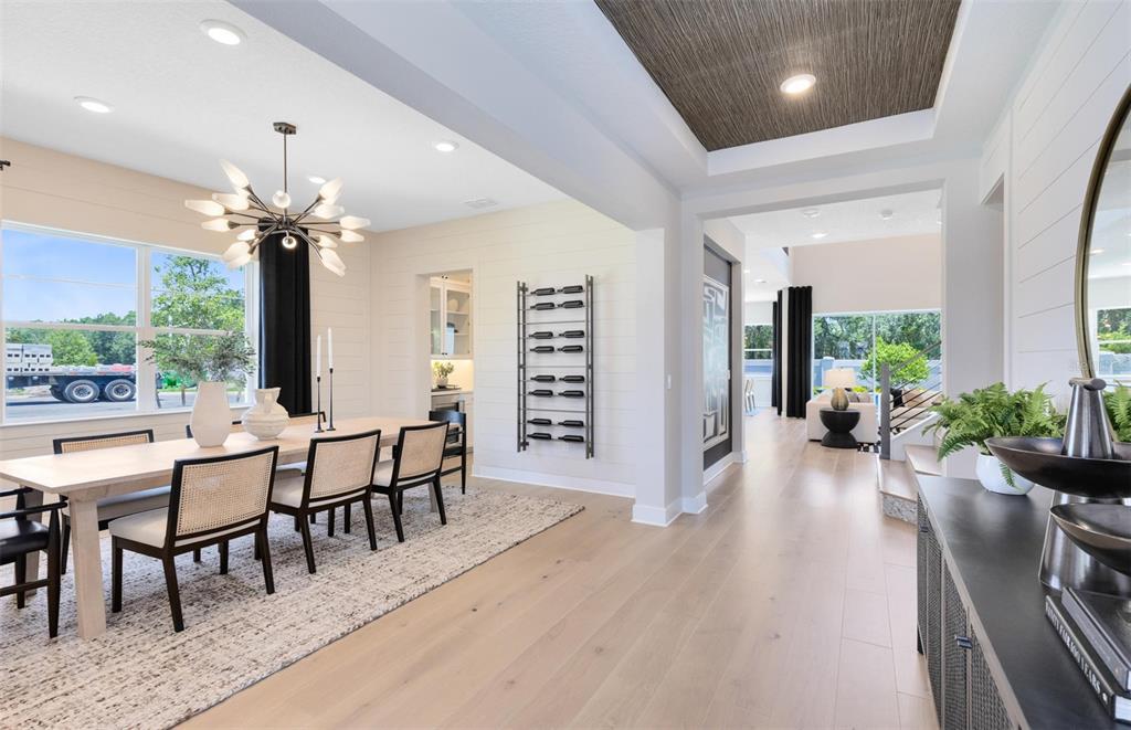 A dining room with a modern chandelier, cane-back chairs, and a wall-mounted wine rack — 16920 LONE OAK CIRCLE, ORLANDO, FL