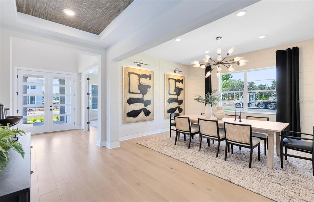 A dining room with a modern chandelier, light wood floors, and shiplap walls — 16920 LONE OAK CIRCLE, ORLANDO, FL