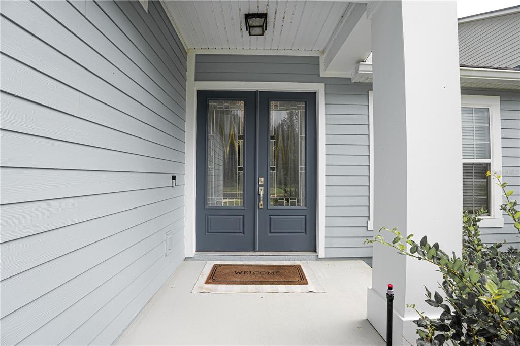 A covered front porch features light blue siding, a double door entrance, and a welcome mat — 782 SILVER LANDING DRIVE, ST AUGUSTINE, FL