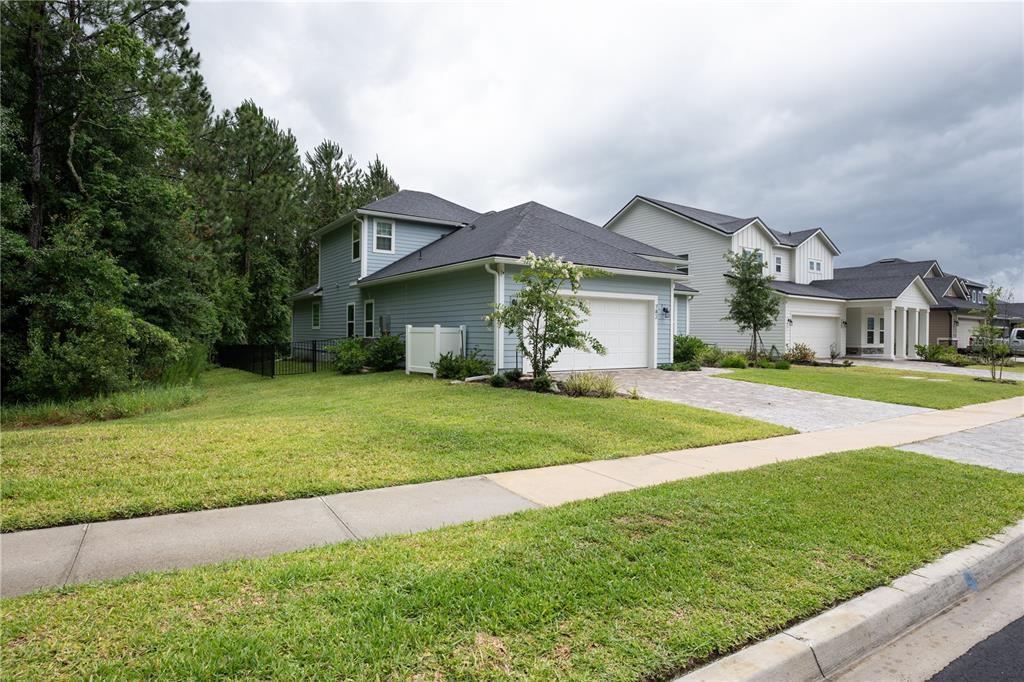 A light blue two-story house with a two-car garage sits next to a wooded area — 782 SILVER LANDING DRIVE, ST AUGUSTINE, FL