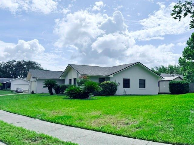 A light-colored, single-story house with a gray roof sits behind a large green lawn — 298 QUAIL COURT, CASSELBERRY, FL
